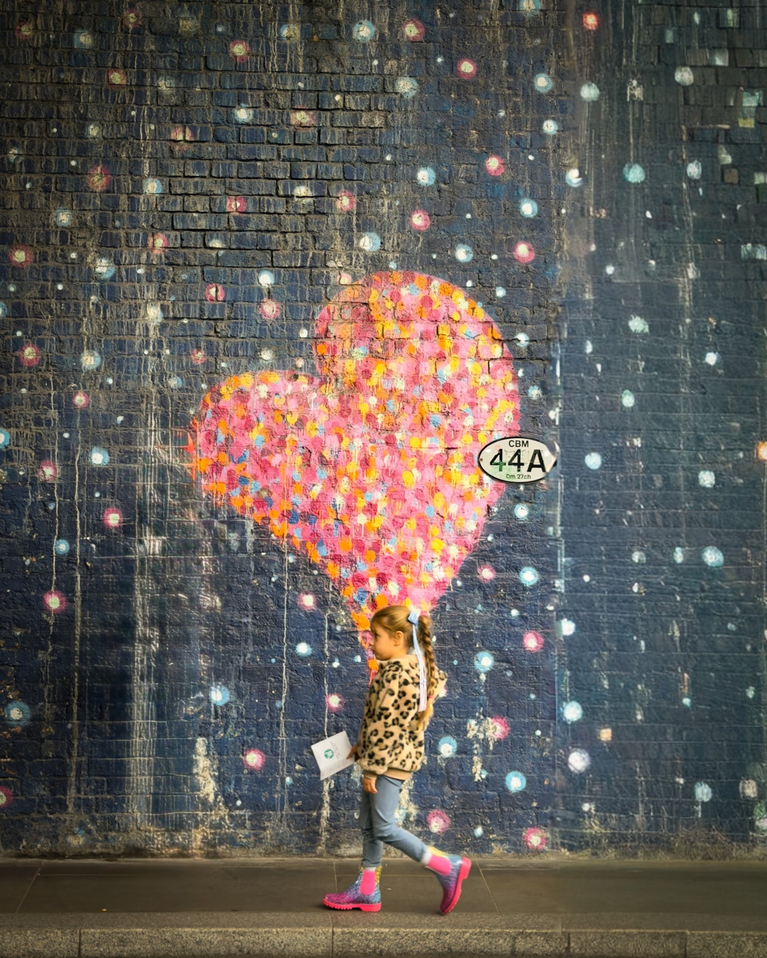 Child walking past a painted heart mural