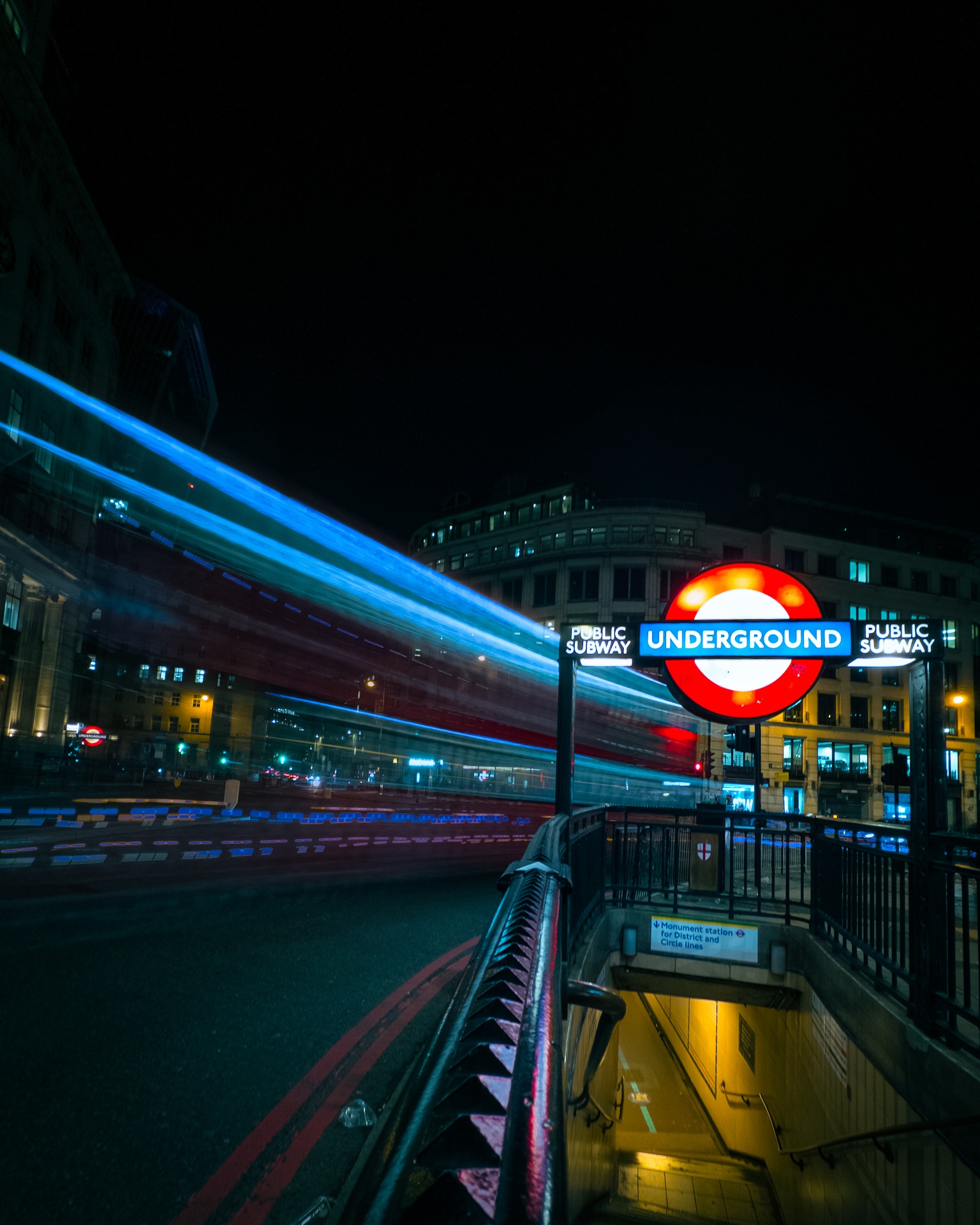 London Underground sign with bus light trails at night
