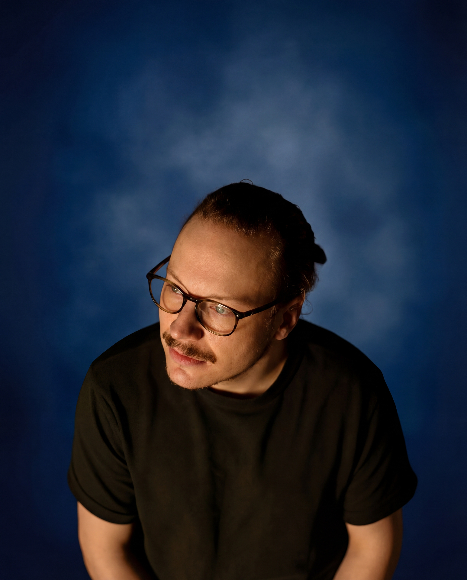 Moody blue studio portrait with glasses